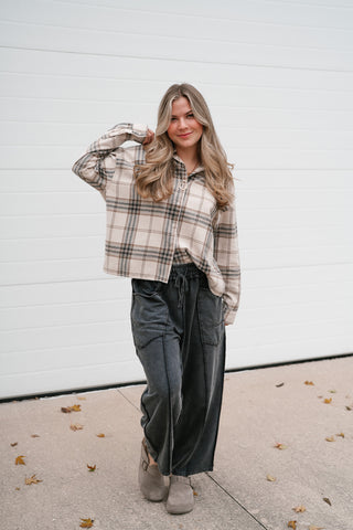 Model with a hand in her hair wearing the relaxed khaki plaid long sleeve button down top