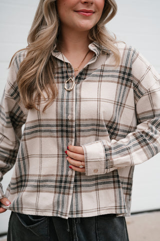 Close-up of the cream and black plaid button down shirt showing the collar, buttons and cuff