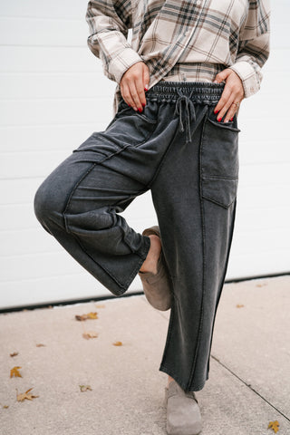 Model lifting one knee to show the relaxed fit of the Next Stop washed black utility barrel leg pants
