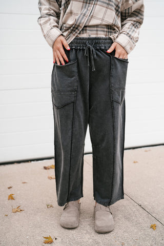 Front view of the washed black utility barrel leg pants styled with a khaki plaid button down