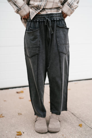 Close-up front view of the black mineral wash barrel pants showing the oversized patch pockets and exposed seams