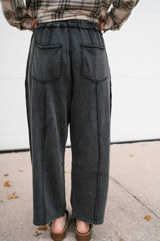 Back view of the washed black utility barrel leg pants with back patch pockets and exposed seams