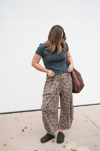 Full-length view of the black Atlas Crew Tee styled with relaxed printed pants and black clogs