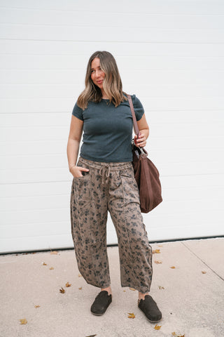Front view of the We The Free Atlas Crew Tee in black worn with printed pants and a brown shoulder bag