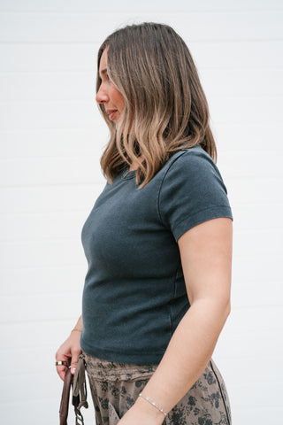 Side view of the fitted black crew neck tee showing the short sleeve and body-skimming fit