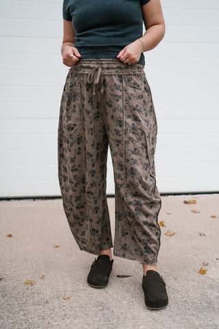 Model holding the waistband of the mocha floral print barrel pants