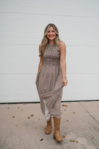 Full-length front view of the Elodie brown gingham smocked midi dress with cowboy boots