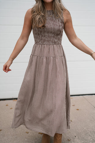 Model in the brown and white gingham midi dress showing the fitted smocked bodice and flowy A-line skirt