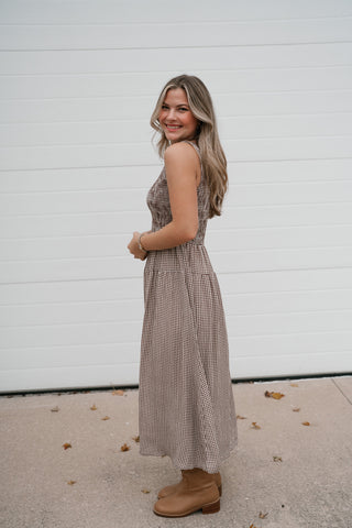 Side view of the brown gingham smocked midi dress showing the fitted bodice and skirt length