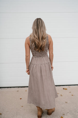 Back view of the brown gingham sleeveless smocked midi dress with tan boots