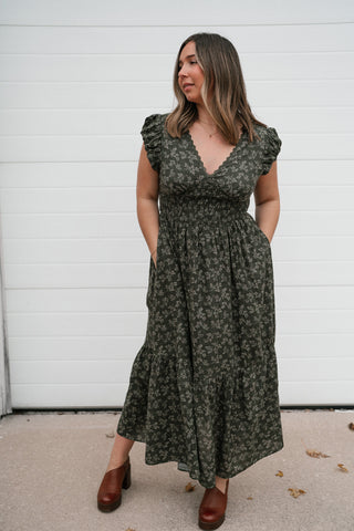 Front view of the olive green floral midi dress with pockets, smocked waist and flutter sleeves
