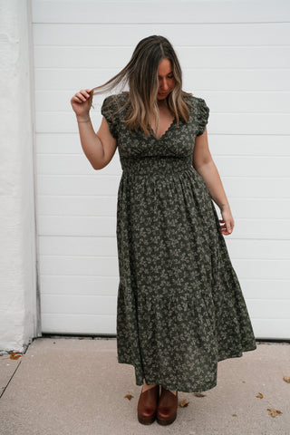 Model touching her hair in the dark green floral print V-neck midi dress