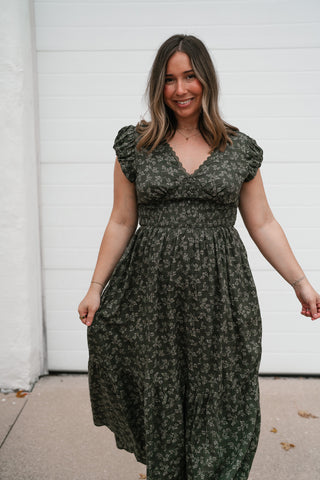 Front view of the dark green floral dress showing the V-neckline, smocked bodice and tiered skirt
