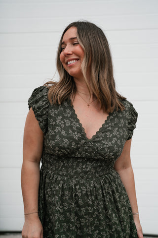 Close-up of the olive floral V-neck dress showing the flutter sleeves and smocked waist