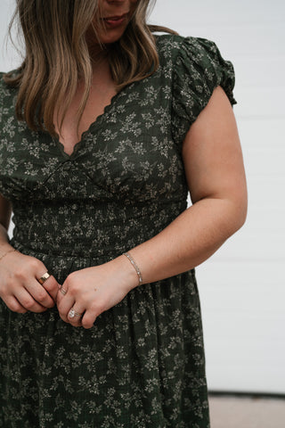 Close-up of the green floral print, ruffled flutter sleeve and V-neckline on the Evergreen Fields dress