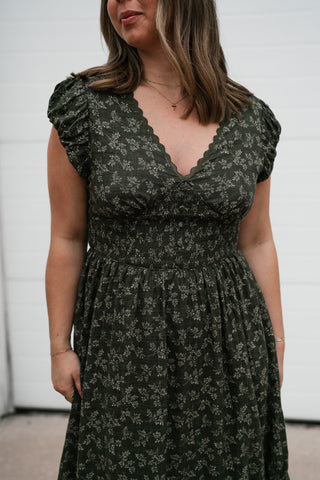 Close-up of the olive floral midi dress's smocked waist, V-neck and flutter sleeves
