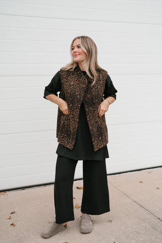 Woman wearing the Out of Office relaxed leopard print puffer vest in brown and black over a black tee and wide-leg pants