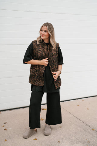 Model holding the front of the brown and black leopard vest showing the single-button closure