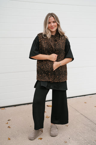 Smiling model in the oversized leopard print vest layered over a black short sleeve top