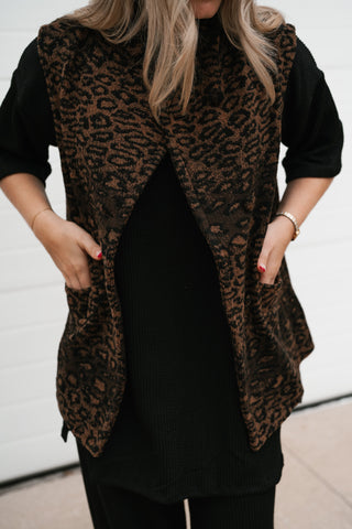 Close-up of the brown and black leopard print vest with hands in the front patch pockets