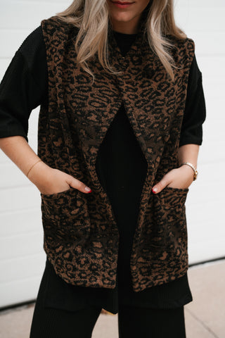 Close-up of the relaxed leopard vest's front pockets and split hem over a black outfit