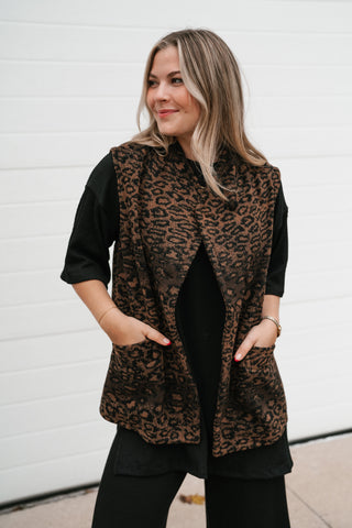 Model smiling with hands in pockets of the brown leopard print puffer vest