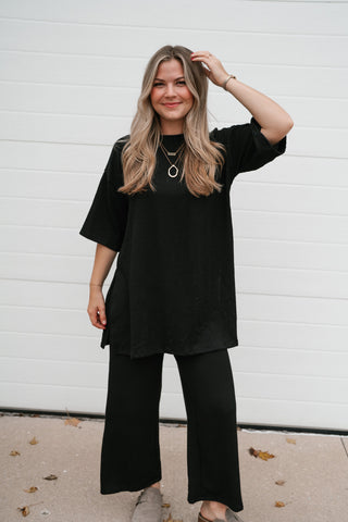 Model with a hand in her hair wearing the Always Cozy black ribbed set top and pants