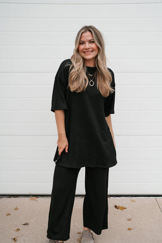 Front view of the relaxed black ribbed top with elbow-length dolman sleeves