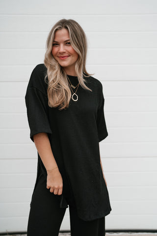 Smiling model in the black ribbed oversized top with the matching ribbed pants