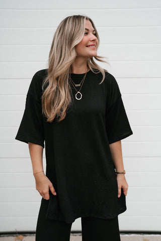 Model looking to the side in the black ribbed dolman sleeve top