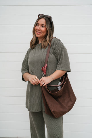 Waist-up view of the oversized olive ribbed tee showing the dropped shoulders and tunic length