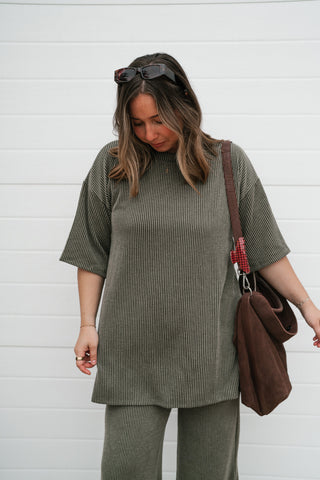 Model looking down in the olive green ribbed oversized short sleeve top