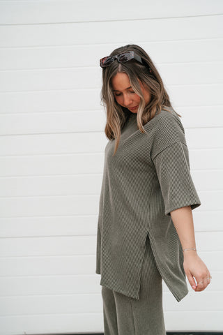 Side view of the olive ribbed tunic top showing the side slit and relaxed fit