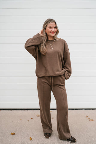 Full-length view of the mocha ribbed matching lounge set with crewneck top, wide leg pants and sneakers