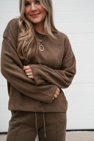 Smiling model in the mocha ribbed crewneck top with wide long sleeves and the matching drawstring pants