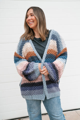 Model smiling in the chunky crochet open cardigan with multicolor stripes and ribbed cuffs