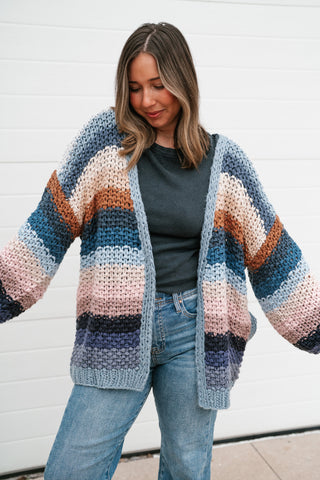 Model with arms out showing the drapey open front and wide striped sleeves of the oversized knit cardigan