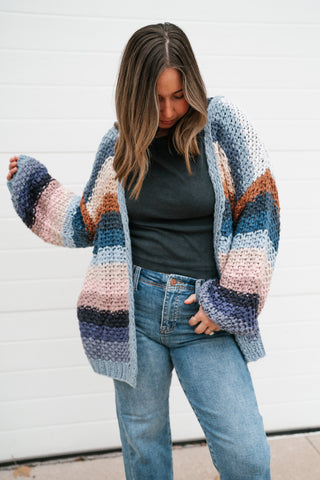 Model with one hand in her jeans pocket wearing the oversized multicolor striped open cardigan