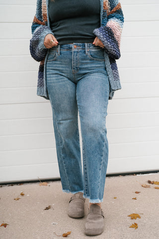 Front view of the Risen Avery medium wash high rise ankle straight jeans with frayed hem and suede clogs