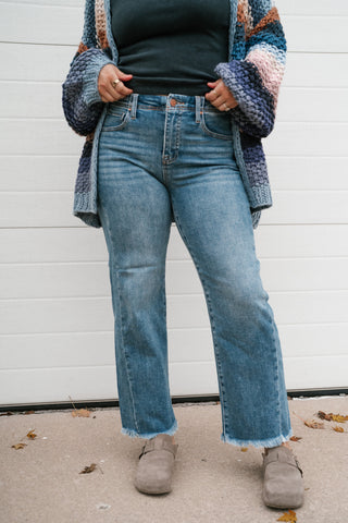 Medium wash high rise ankle jeans with hands in the front pockets