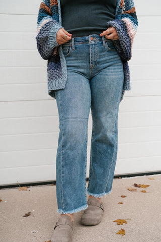 Model holding the waistband of the high rise medium wash Risen straight leg jeans