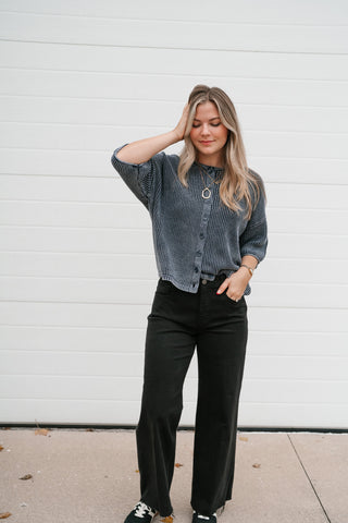 Full-length view of the navy short sleeve button front sweater styled with black trousers and sneakers