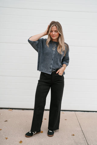 Model with hand in pocket wearing the washed navy ribbed knit cardigan buttoned as a top