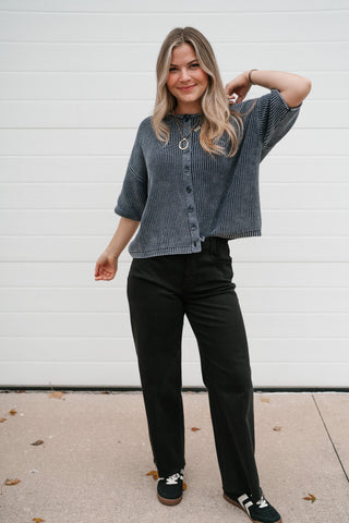 Front view of the boxy navy knit cardigan with drop shoulders and elbow sleeves, worn with black pants