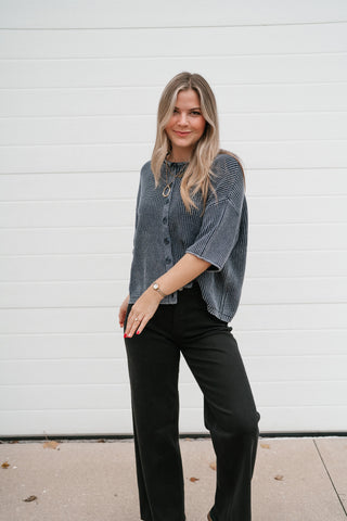 Angled view of the navy vintage-wash short sleeve cardigan styled with black straight-leg pants