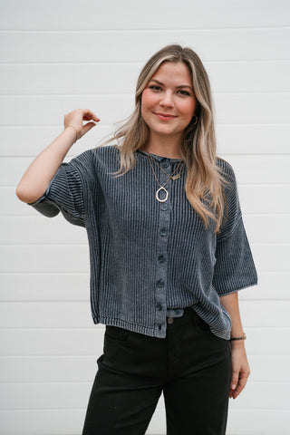 Model smiling in the faded navy ribbed button front sweater with elbow-length sleeves