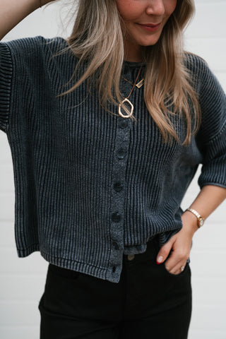 Close-up of the navy cardigan's round neckline, ribbed knit and buttons