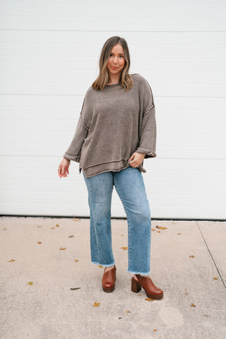 Full-length view of the washed brown dolman sweater styled with cropped jeans and brown platform clogs