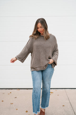 Model walking in the washed brown dolman sleeve sweater with light wash jeans