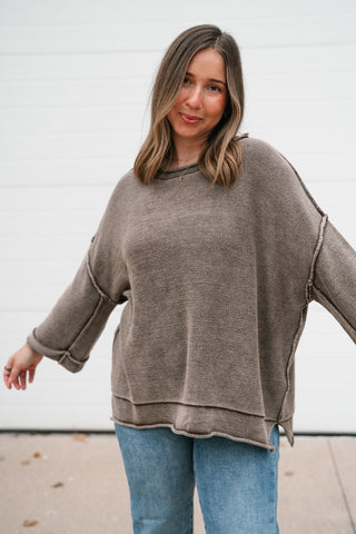 Model with arms out showing the relaxed fit and wide dolman sleeves of the brown knit sweater